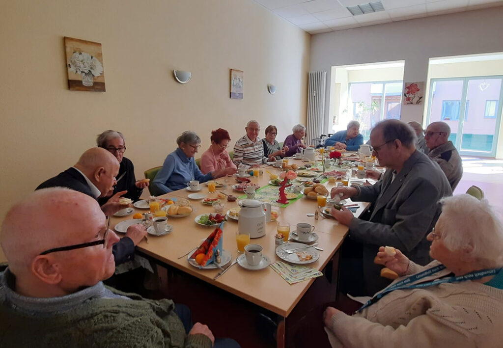 Gruppe von Senioren beim Fr&uuml;hst&uuml;ck in einer Gemeinschaftseinrichtung.