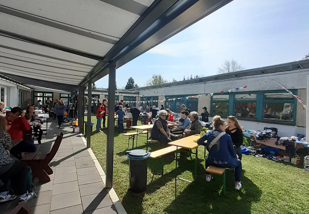 Menschen sitzen und stehen im Freien bei einem sozialen Event.