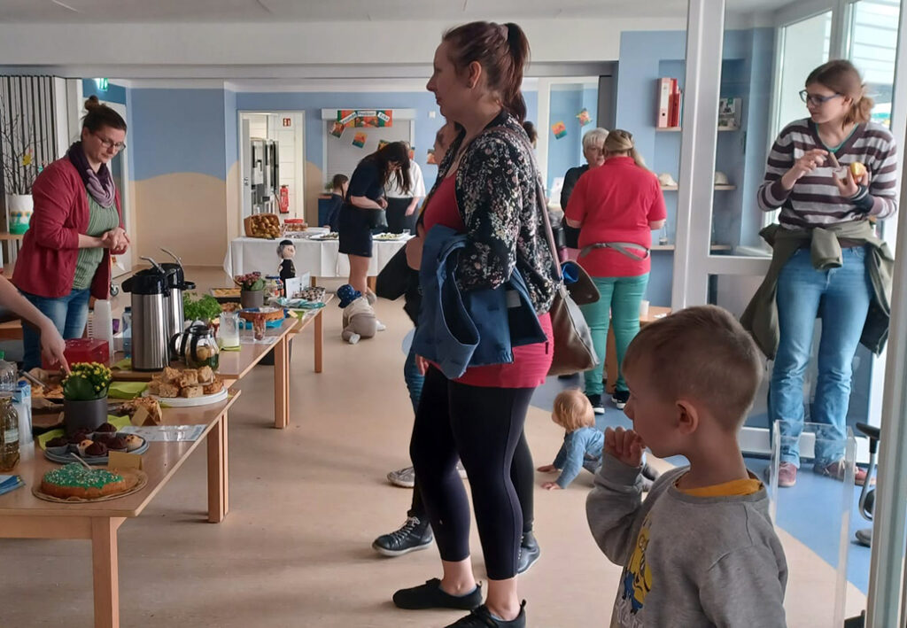 Menschen in einem Gemeinschaftsraum mit Essenstischen.