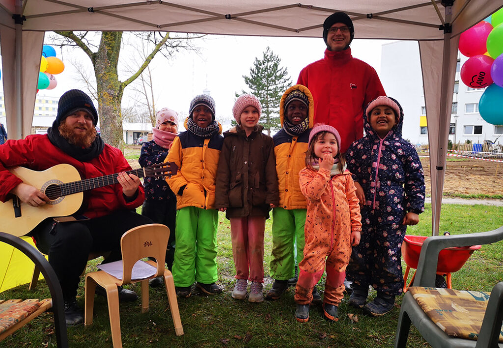 Gruppe von Kindern und zwei Erwachsenen unter einem Zelt im Freien
