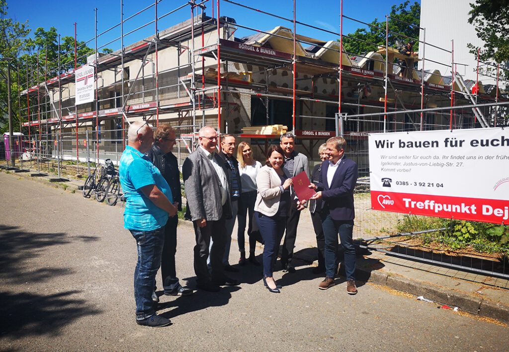 Gruppe von Menschen vor einem Gebäude in Renovierung mit einem Schild der AWO
