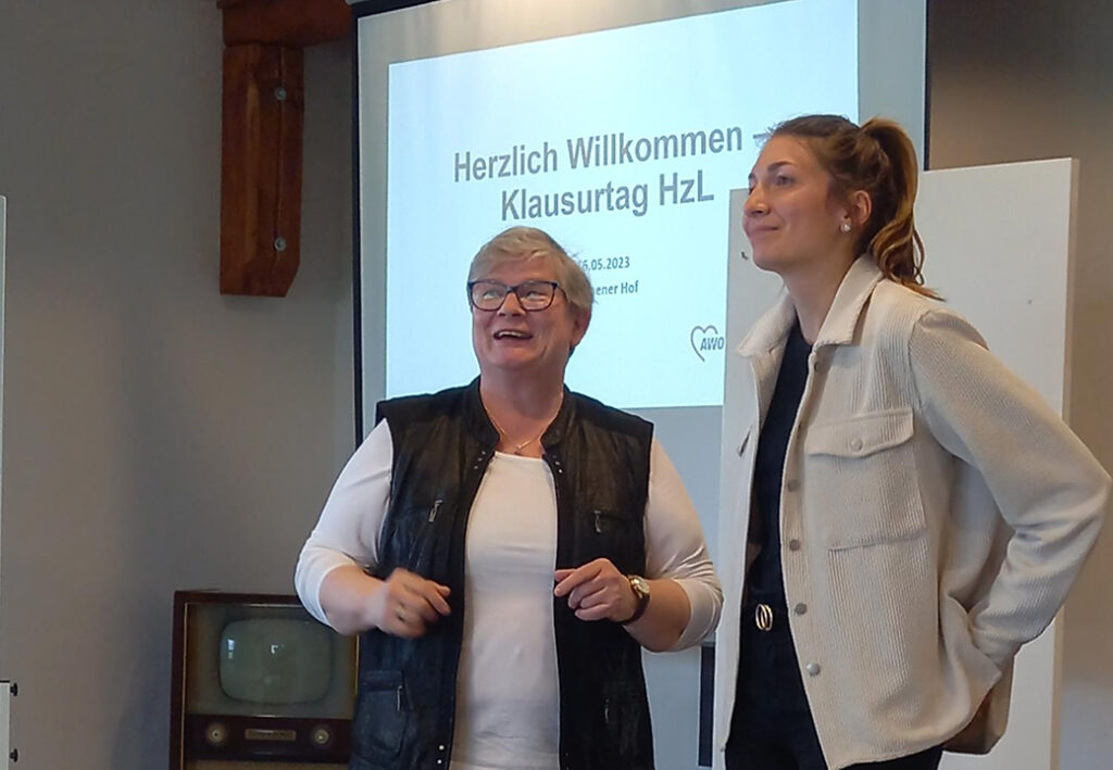 Zwei Menschen vor einer Projektionsleinwand mit Begr&uuml;&szlig;ungsfolie