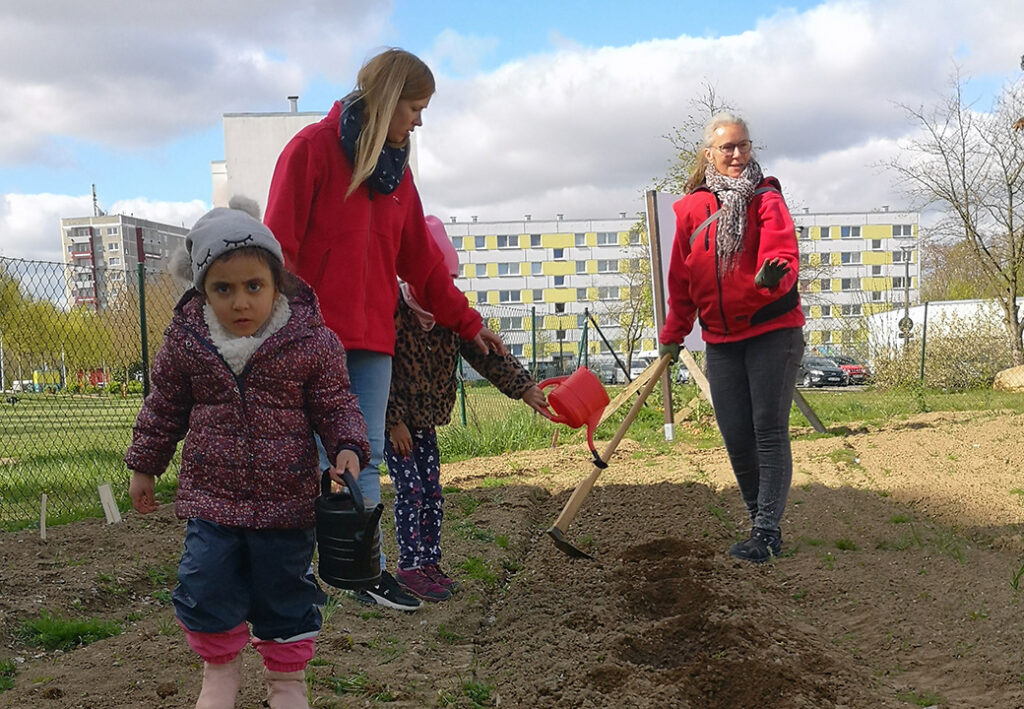 Ein Kind und zwei Erwachsene arbeiten in einem Garten.