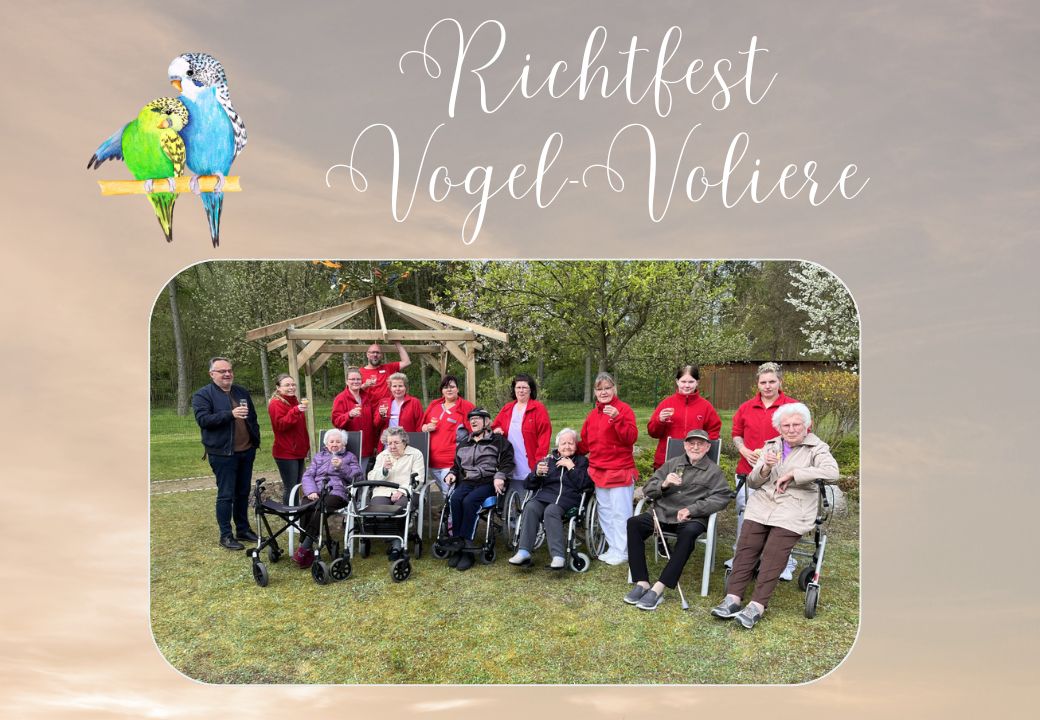 Gruppenfoto von Menschen bei einem Richtfest vor einer Vogelvoliere