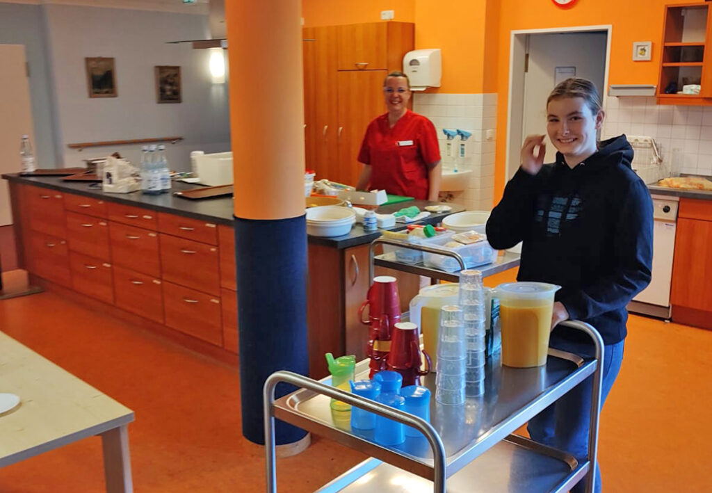 Zwei Personen in einer K&uuml;che mit einem Servierwagen