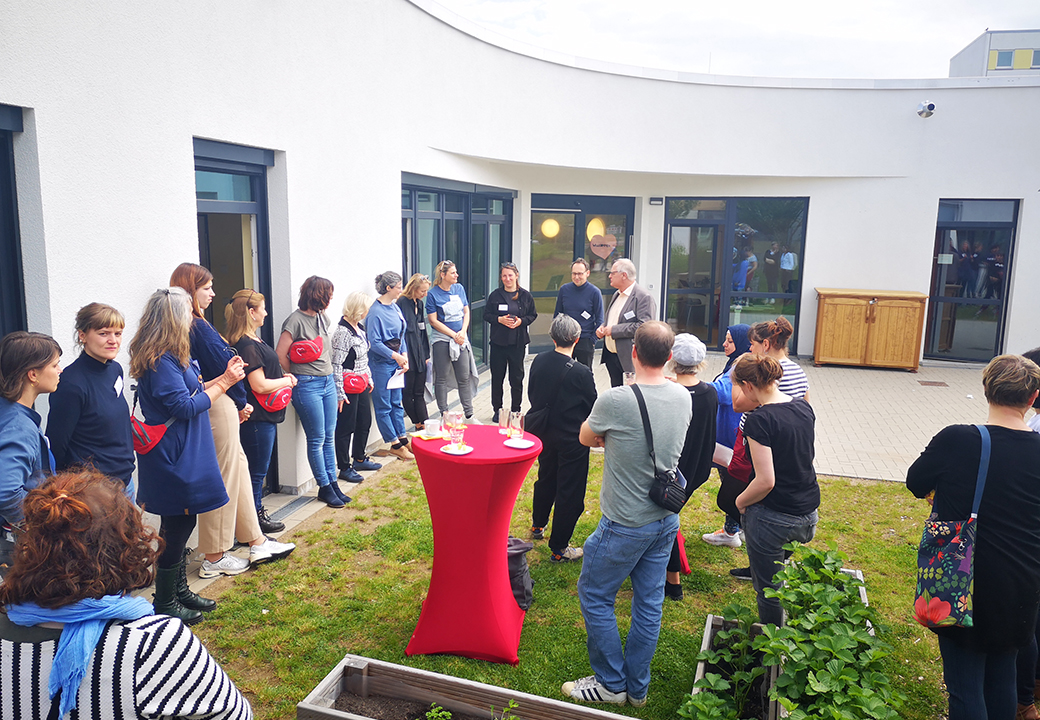 Gruppe von Menschen steht in einem Halbkreis im Freien.