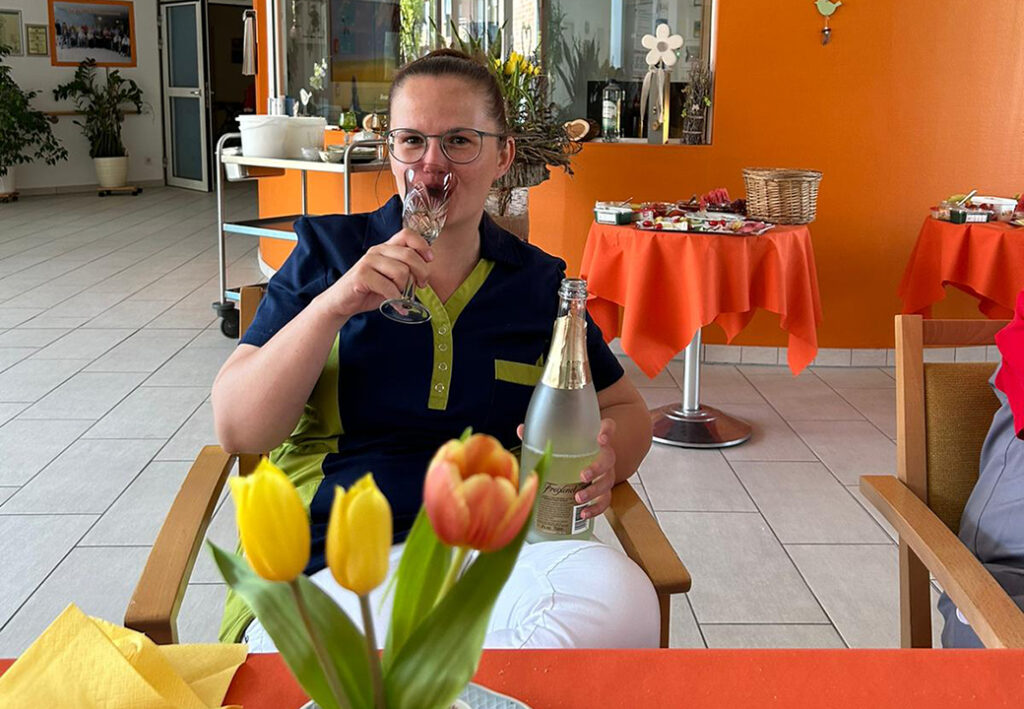 Person sitting in a room holding a champagne bottle and glass.