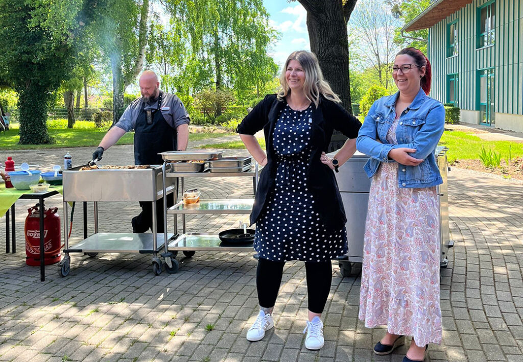 Drei Personen bei einem Grillfest im Freien.