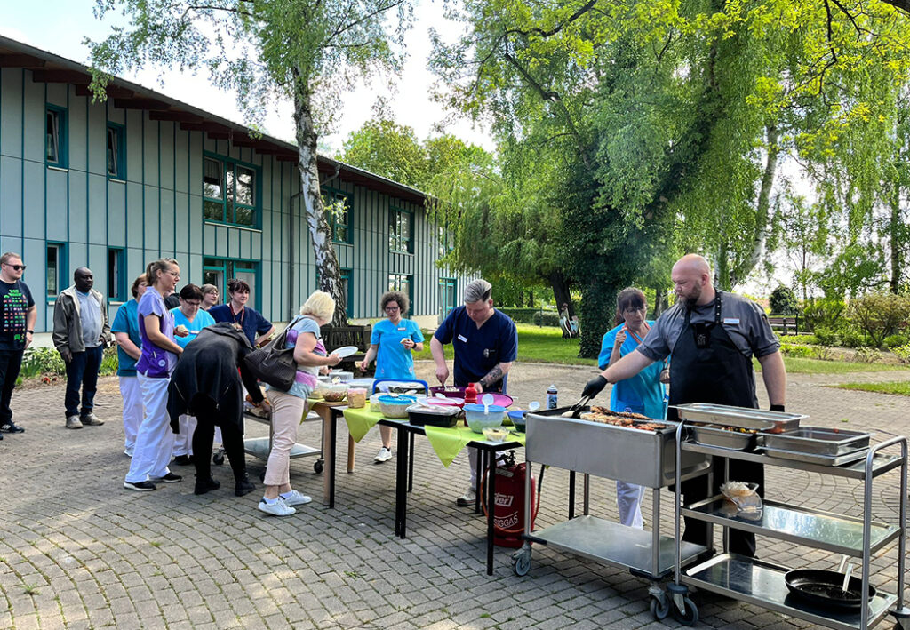 Menschen bei einem Grillfest im Freien vor einem Geb&auml;ude