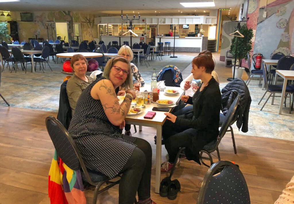 Gruppe von Menschen sitzt an einem Tisch und isst gemeinsam in einem gro&szlig;en Saal.