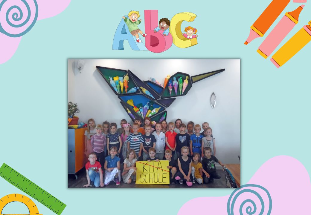 Gruppe von Kindern in einer Bildungseinrichtung, umgeben von bunten Schulutensilien und einer Wanddekoration.