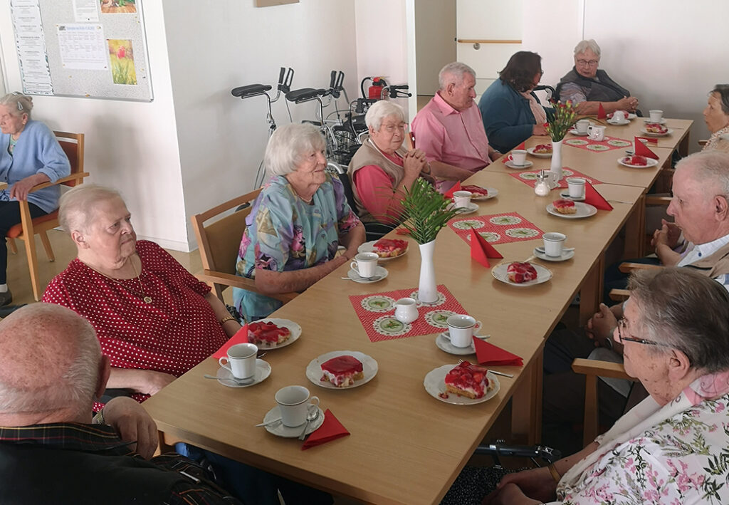 Eine Gruppe &auml;lterer Menschen sitzt gemeinsam an einem Tisch und genie&szlig;t Kaffee und Kuchen.