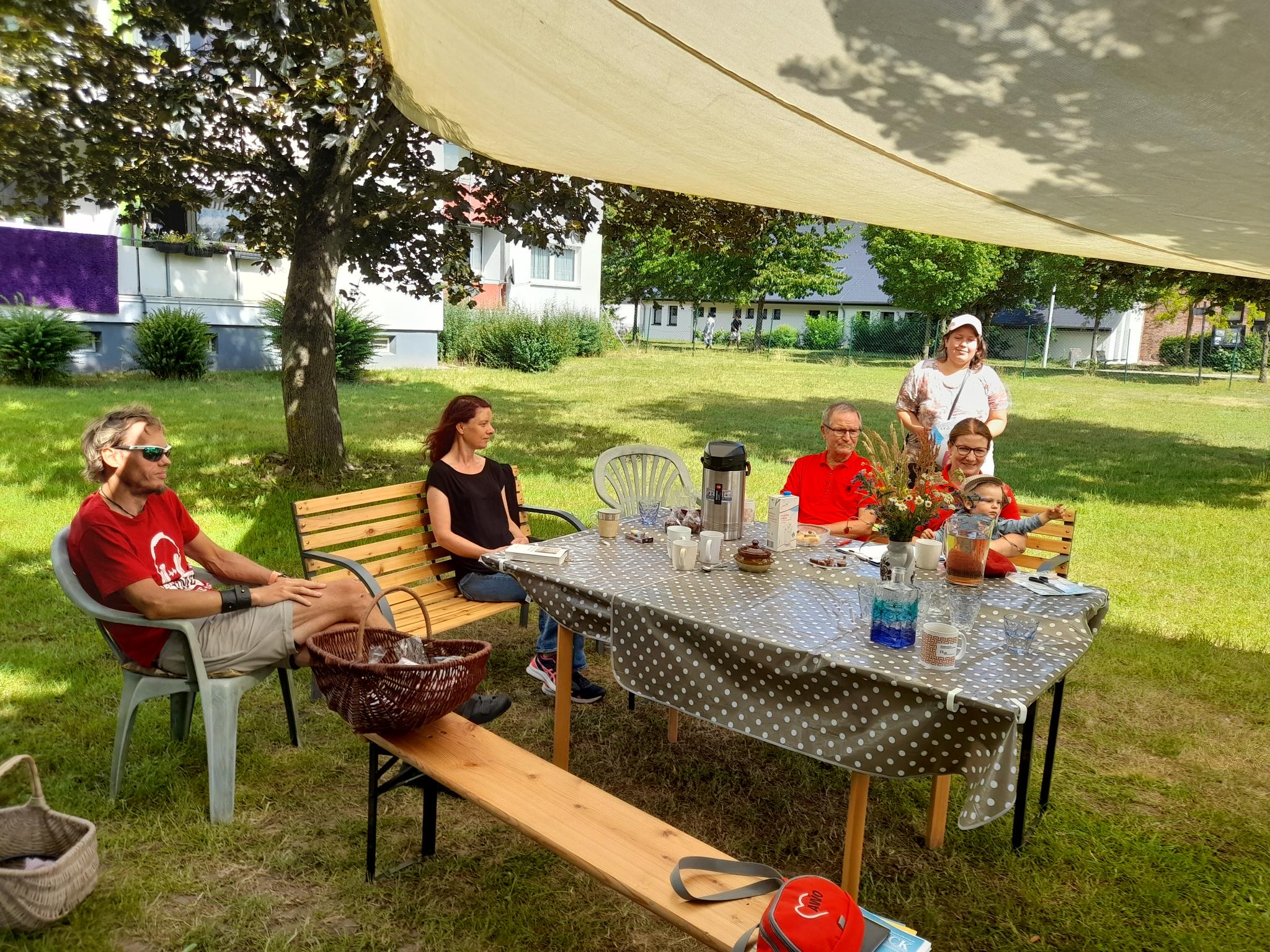 Eine Gruppe von Menschen sitzt an einem Tisch im Freien.