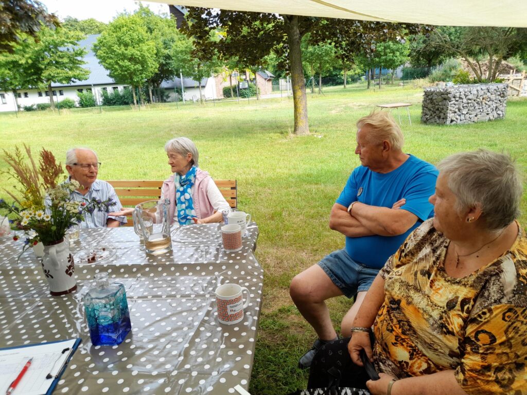 Menschen sitzen an einem Tisch im Freien.