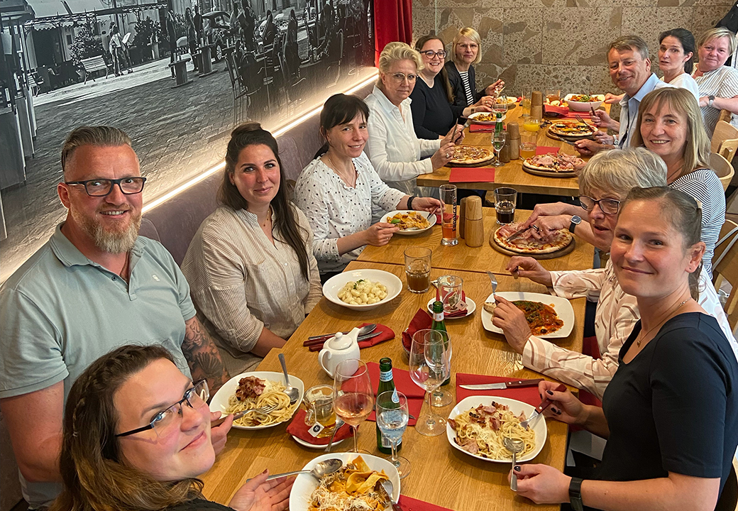 Eine Gruppe von Menschen beim gemeinsamen Essen an einem langen Tisch.