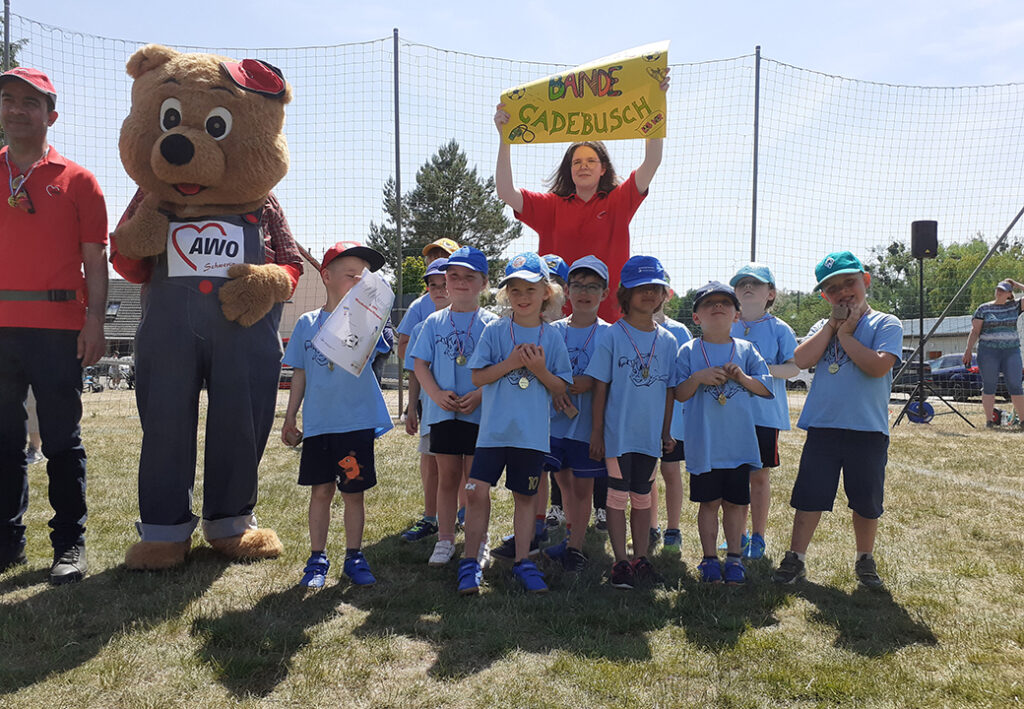 Gruppenfoto mit Kindern und Erwachsenen auf einer Wiese