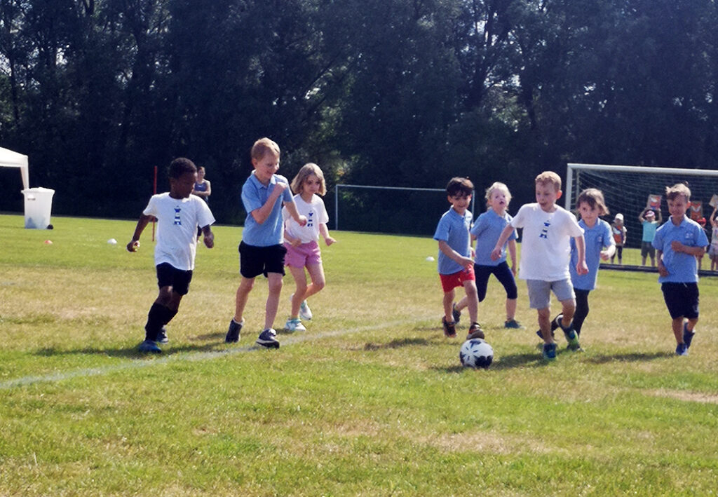 Kinder spielen Fu&szlig;ball auf einem Rasenplatz