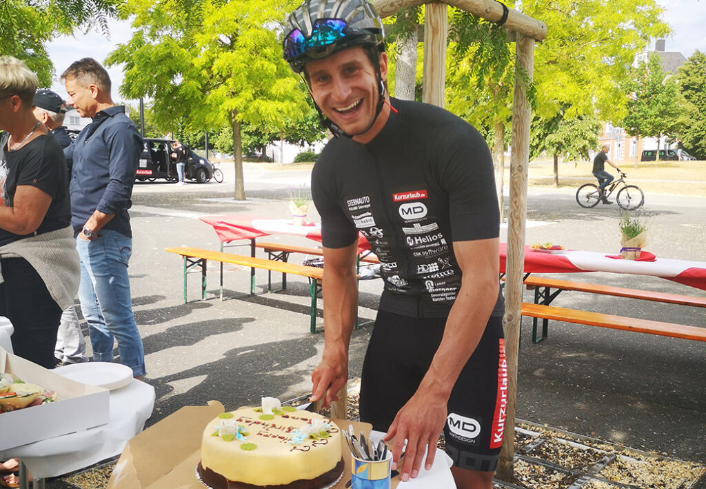 Ein Radfahrer schneidet eine Torte an.