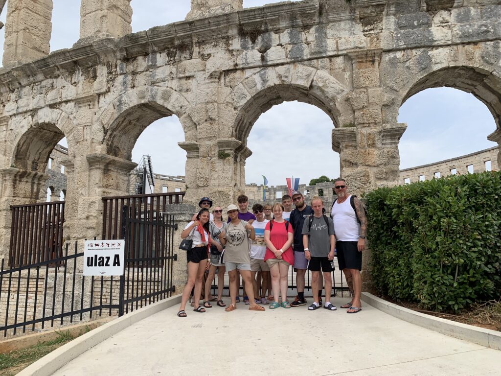 Eine Gruppe von Menschen vor einem historischen Geb&auml;ude mit B&ouml;gen.
