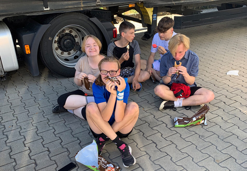 Gruppe von Jugendlichen beim Eisessen neben einem LKW