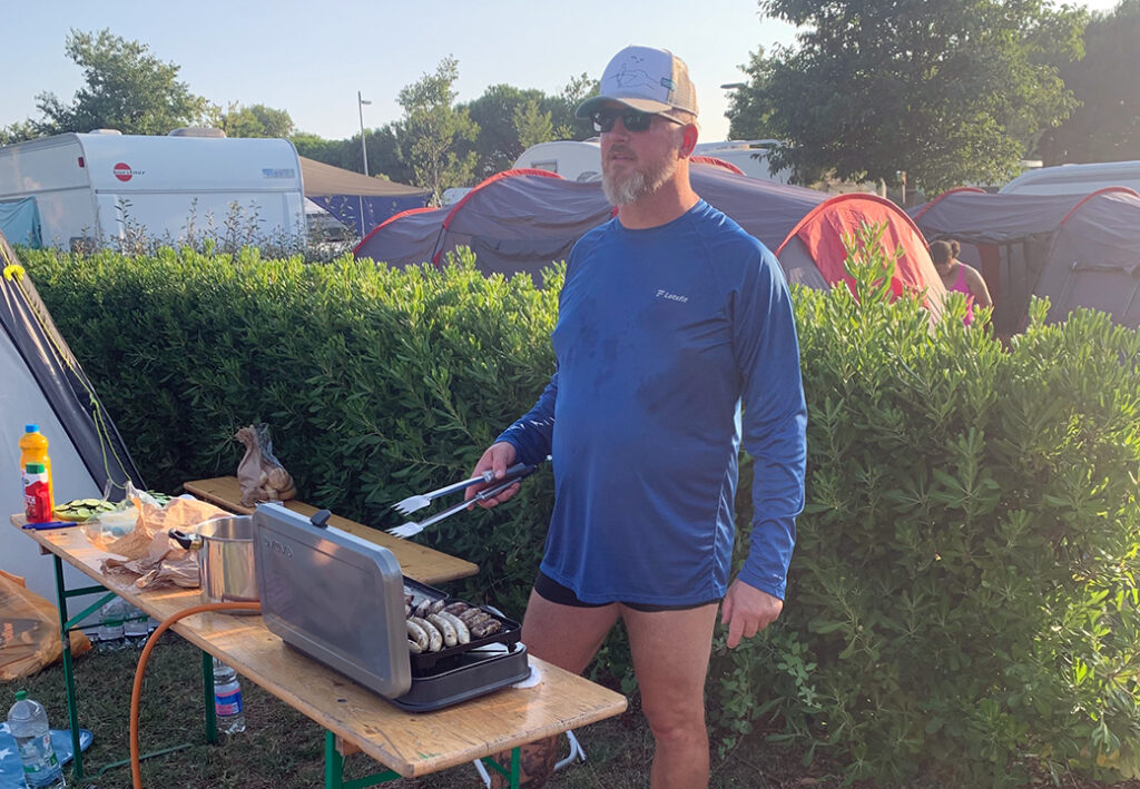 Ein Mann grillt im Freien auf einem Campingplatz.