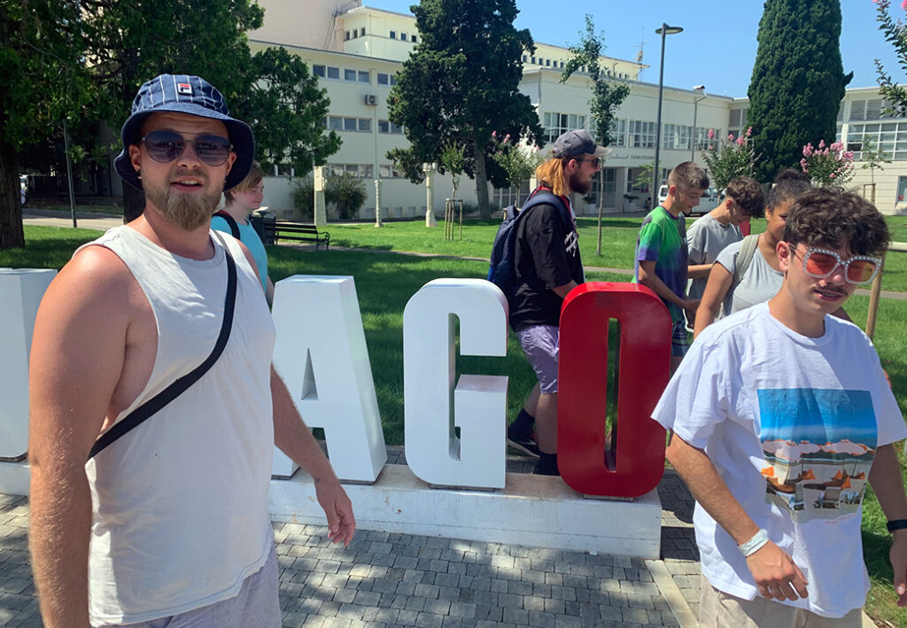 Eine Gruppe von Menschen steht vor gro&szlig;en Buchstaben im Freien.