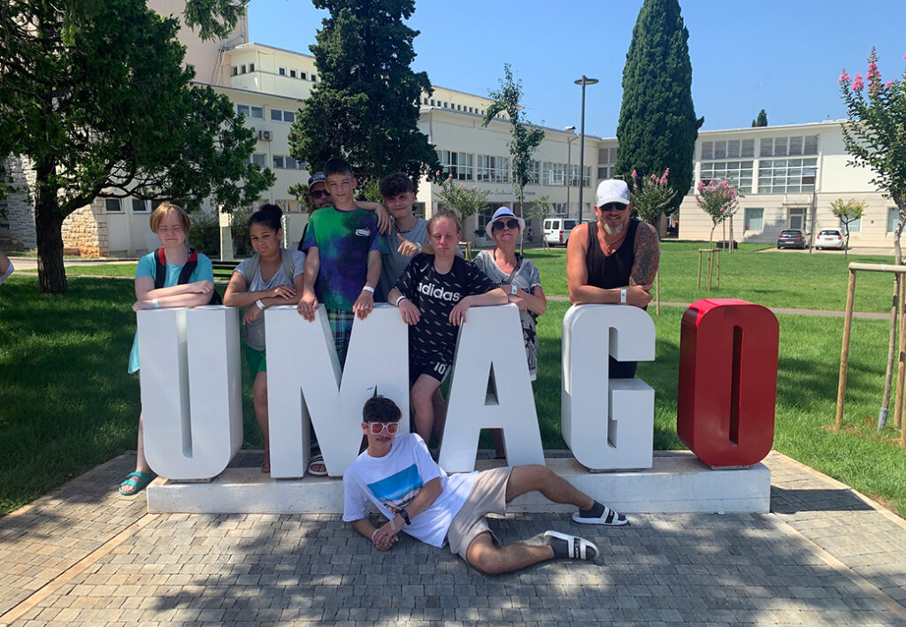 Gruppe von Personen posiert vor einem UMAGO-Schild