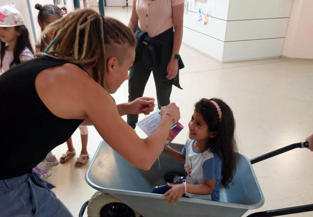 Eine Frau spielt mit einem Kind in einer Schubkarre