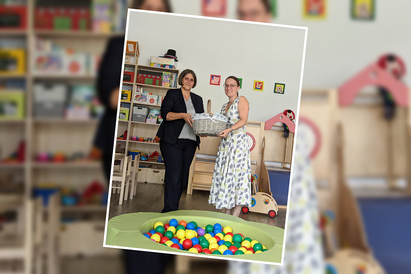 Zwei Frauen in einem Spielzimmer halten zusammen einen Korb.