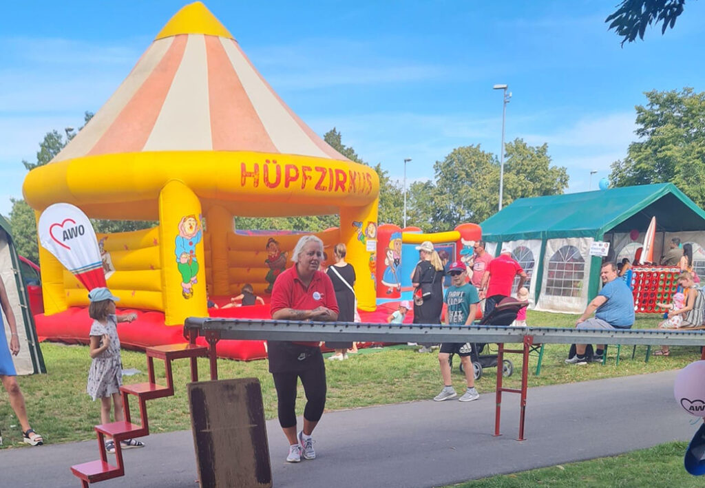 Ein sommerliches Fest mit einem H&uuml;pfzirkus und AWO-Flaggen im Hintergrund.