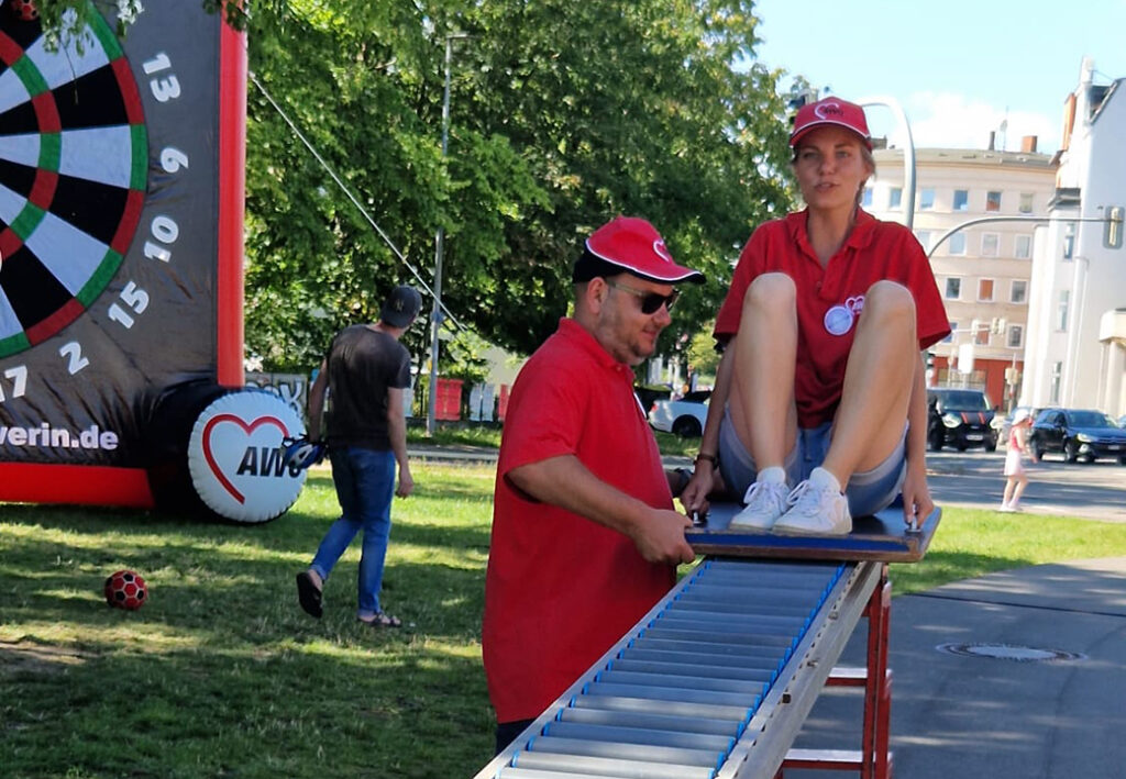 Zwei Personen in roten AWO-Shirts an einer Veranstaltung im Freien.