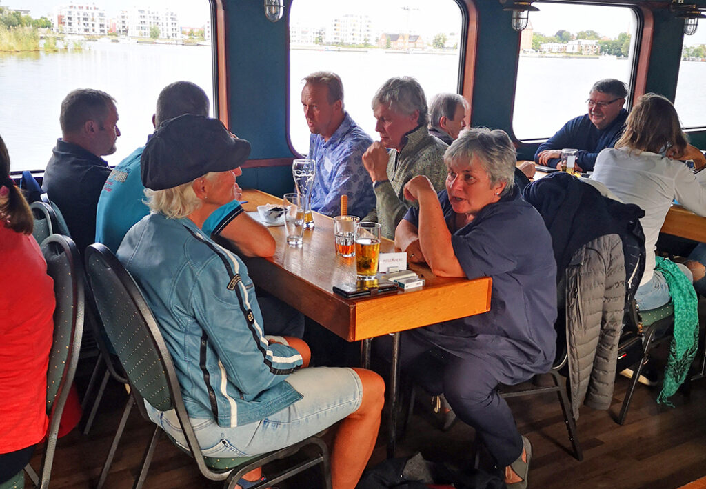 Eine Gruppe von Menschen sitzt in einem Caf&eacute; auf einem Boot.