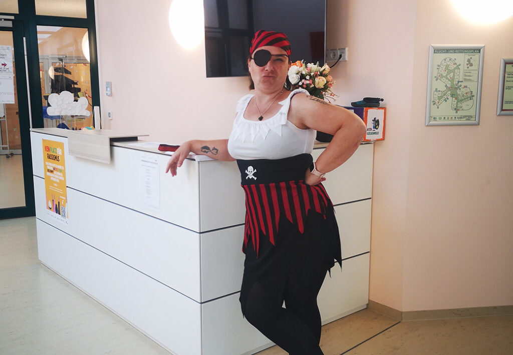 Eine Person in einem Piratenkostüm lehnt an einem Empfangstresen.