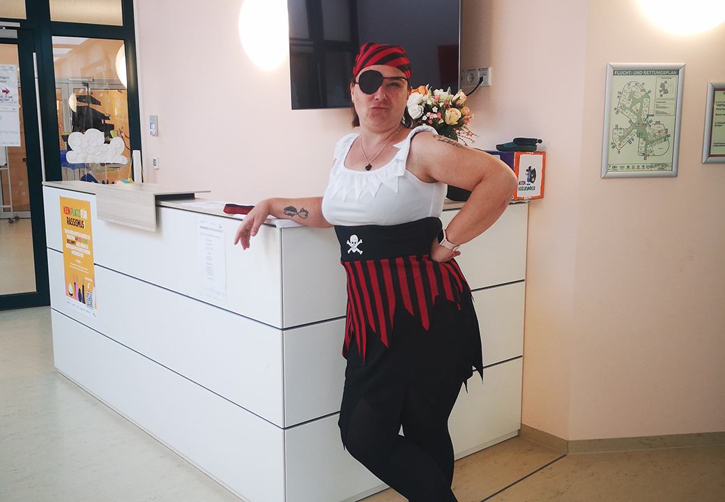 Eine Person in einem Piratenkostüm lehnt an einem Empfangstresen.