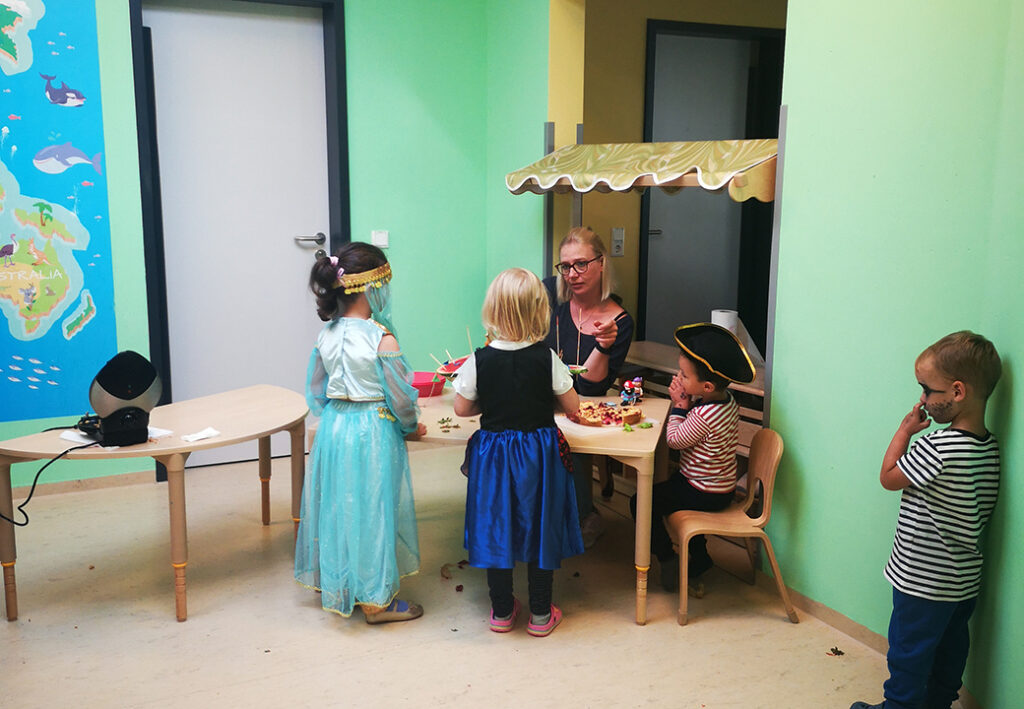 Kinder verkleidet in einem Raum mit Betreuerin