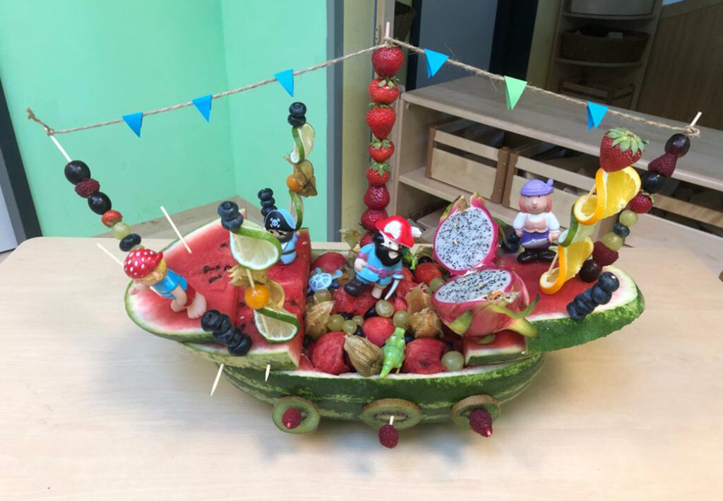 Ein kunstvoll gestaltetes Obstschiff auf einem Tisch.