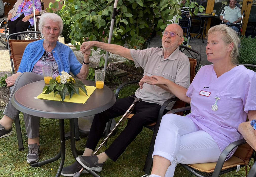 Drei Personen sitzen im Freien an einem Tisch.