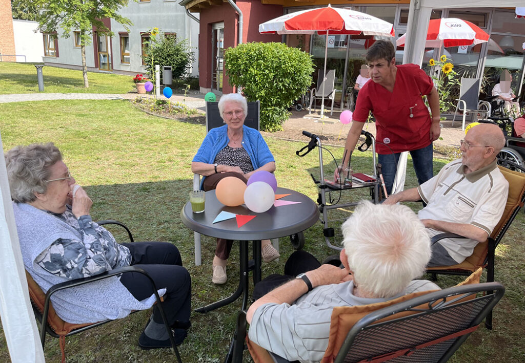 Seniorengruppe sitzt an einem Tisch im Freien.