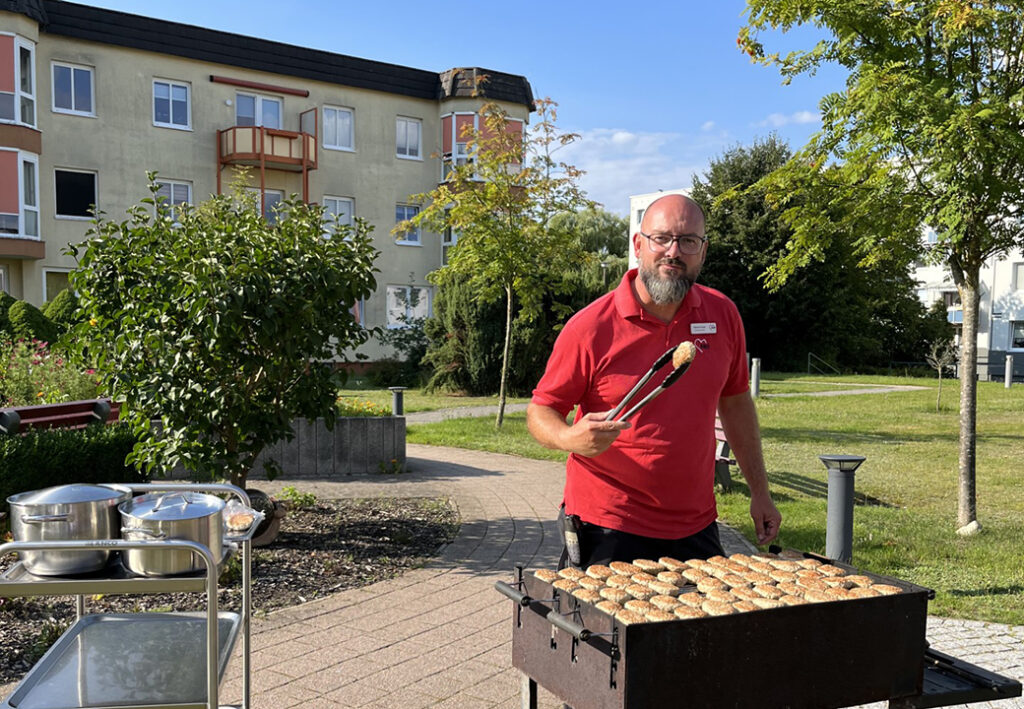 Ein Mann grillt im Freien vor einem Wohngeb&auml;ude
