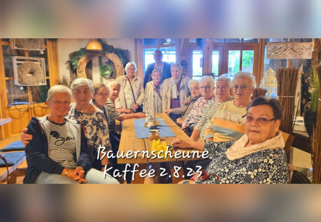 Eine Gruppe &auml;lterer Menschen sitzt an einem langen Holztisch in einer rustikalen Umgebung. Der Text 'Bauernscheune Kaff&eacute;e 2.8.23' ist auf dem Bild zu sehen.