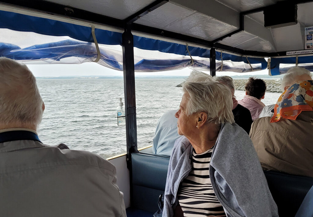 Eine Gruppe &auml;lterer Menschen sitzt in einem Boot mit Blick aufs Meer.