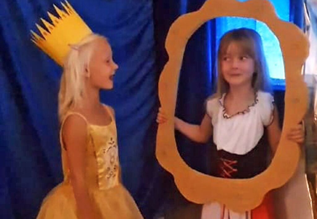 Zwei M&auml;dchen in Kost&uuml;men, eines h&auml;lt einen Rahmen.