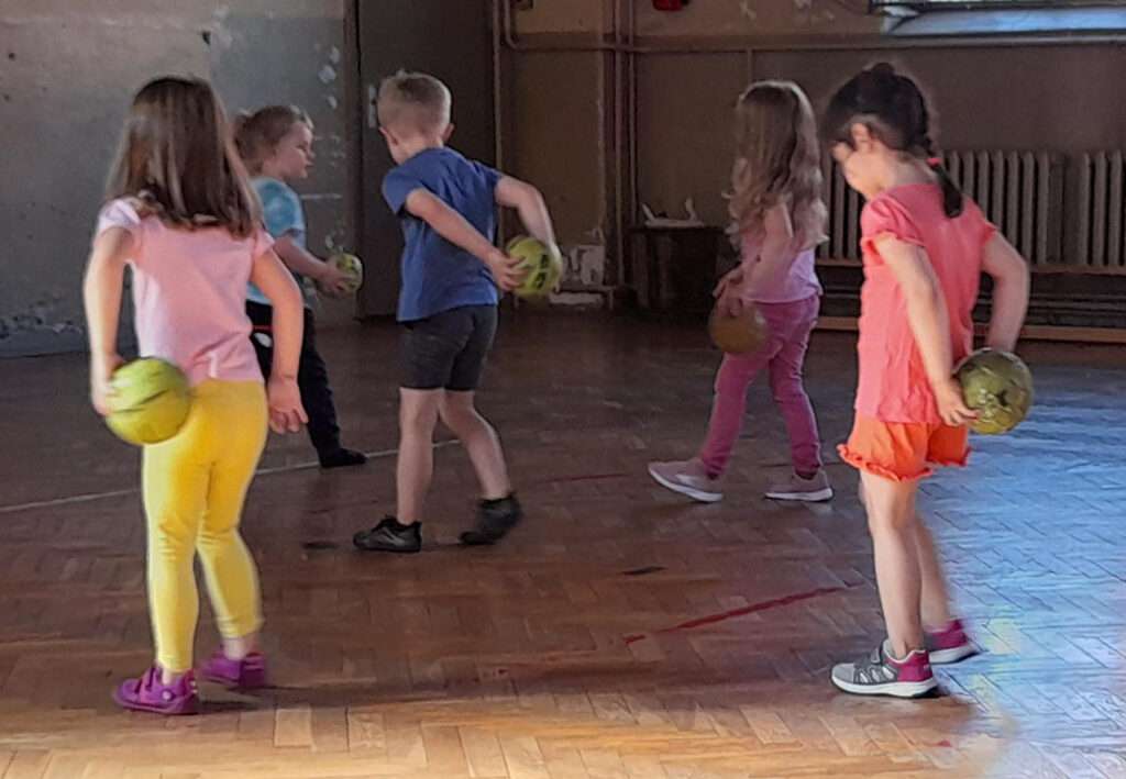 Kinder spielen in einer Halle mit B&auml;llen.