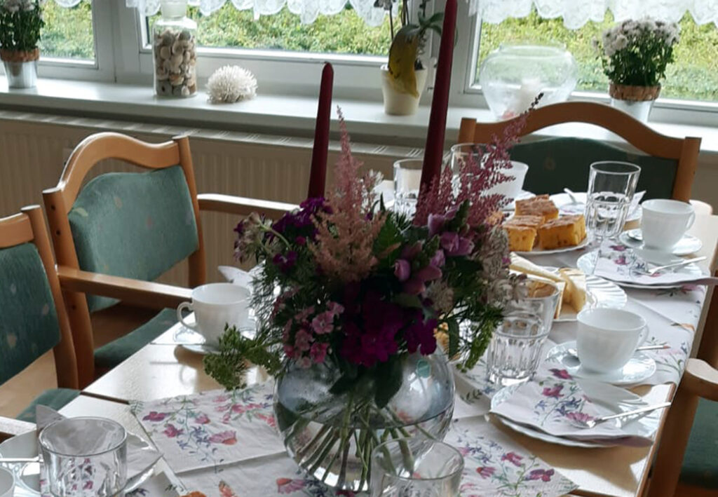 Gedeckter Tisch mit Blumen und Geb&auml;ck