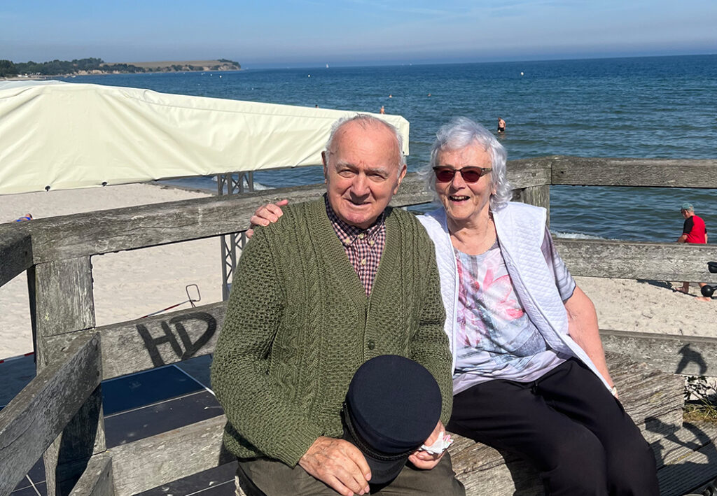 Ein älteres Paar sitzt auf einer Bank mit Blick auf das Meer.