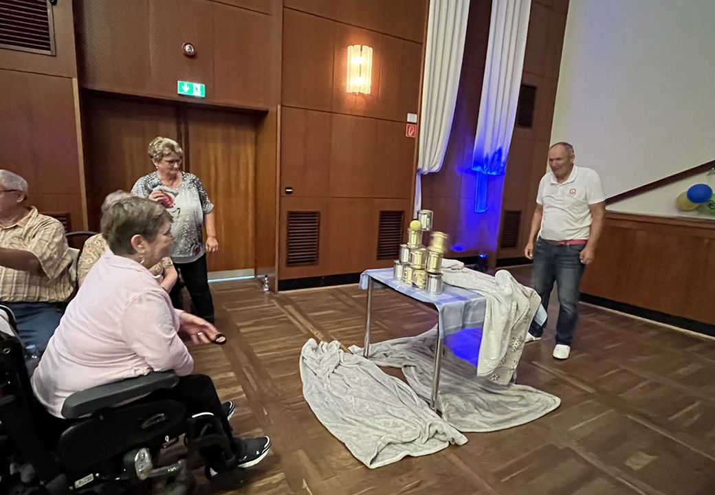 Eine Gruppe von Menschen spielt in einem Innenraum ein Dosenwurfspiel.