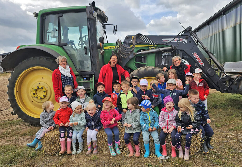 Gruppe von Kindern und Erwachsenen vor einem Traktor