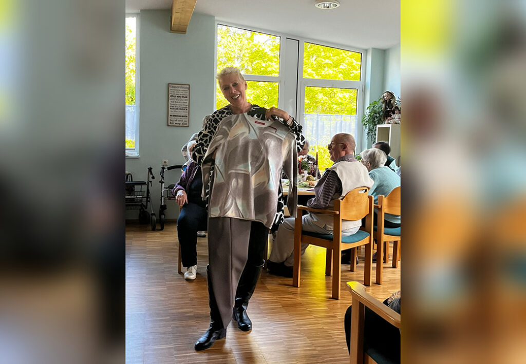 Eine Frau in einem Gemeinschaftsraum zeigt einen Pullover.