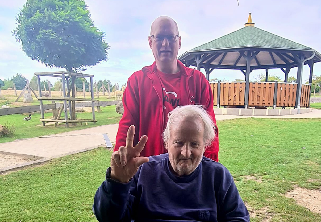 Zwei Männer in einem Park mit Pavillon im Hintergrund