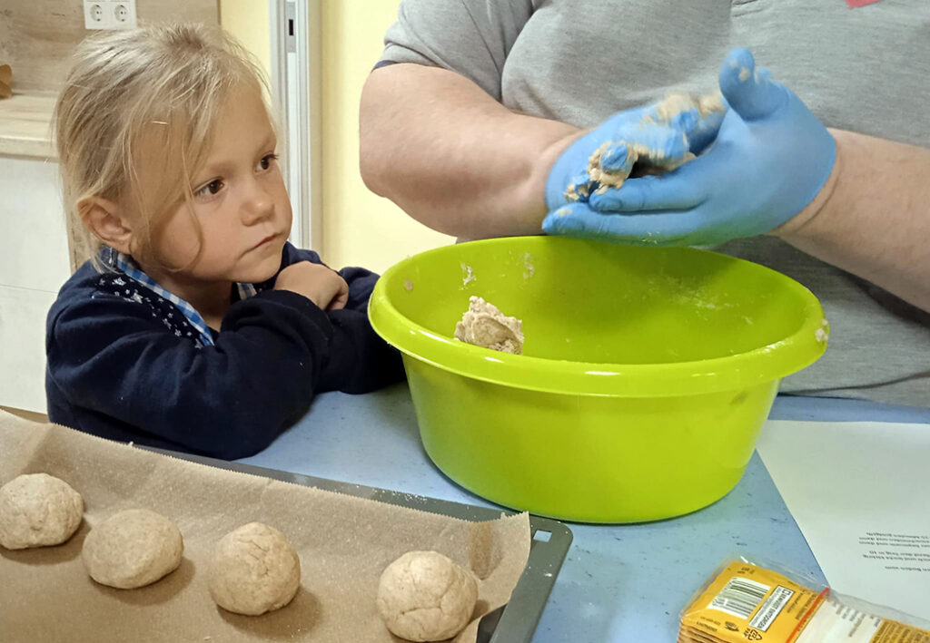 Ein Kind beobachtet einen Erwachsenen beim Zubereiten von Teig.